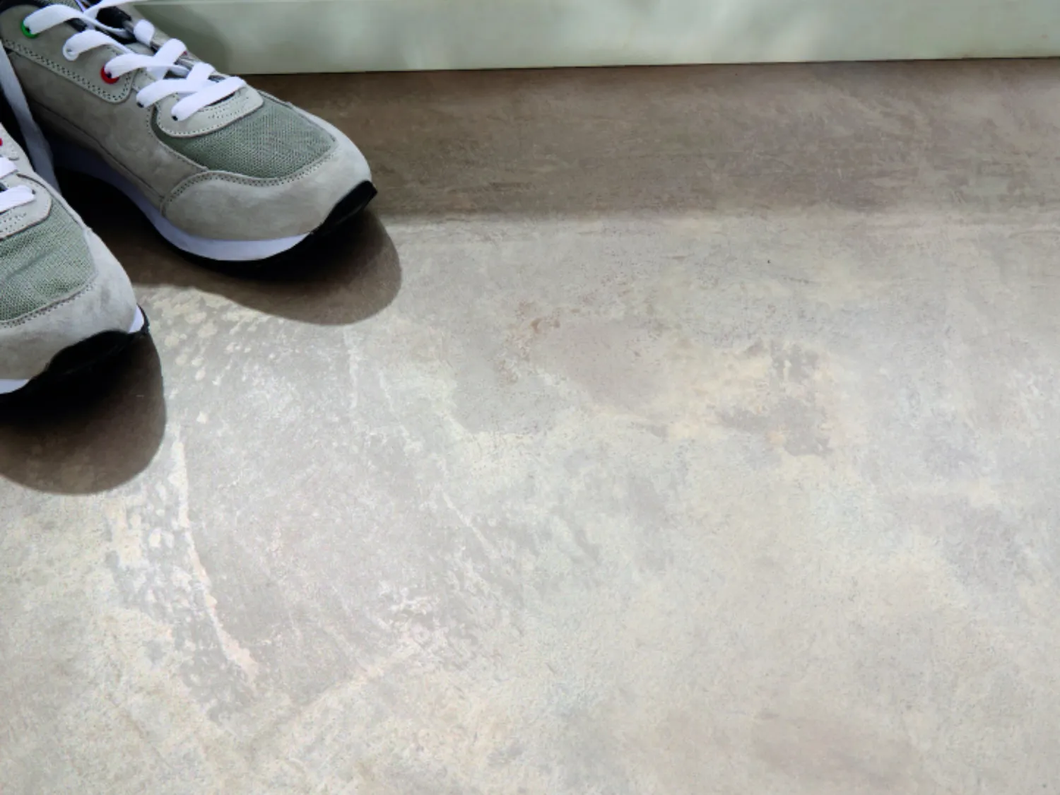 Zwei graue Sportschuhe mit weißen Schnürsenkeln liegen auf
